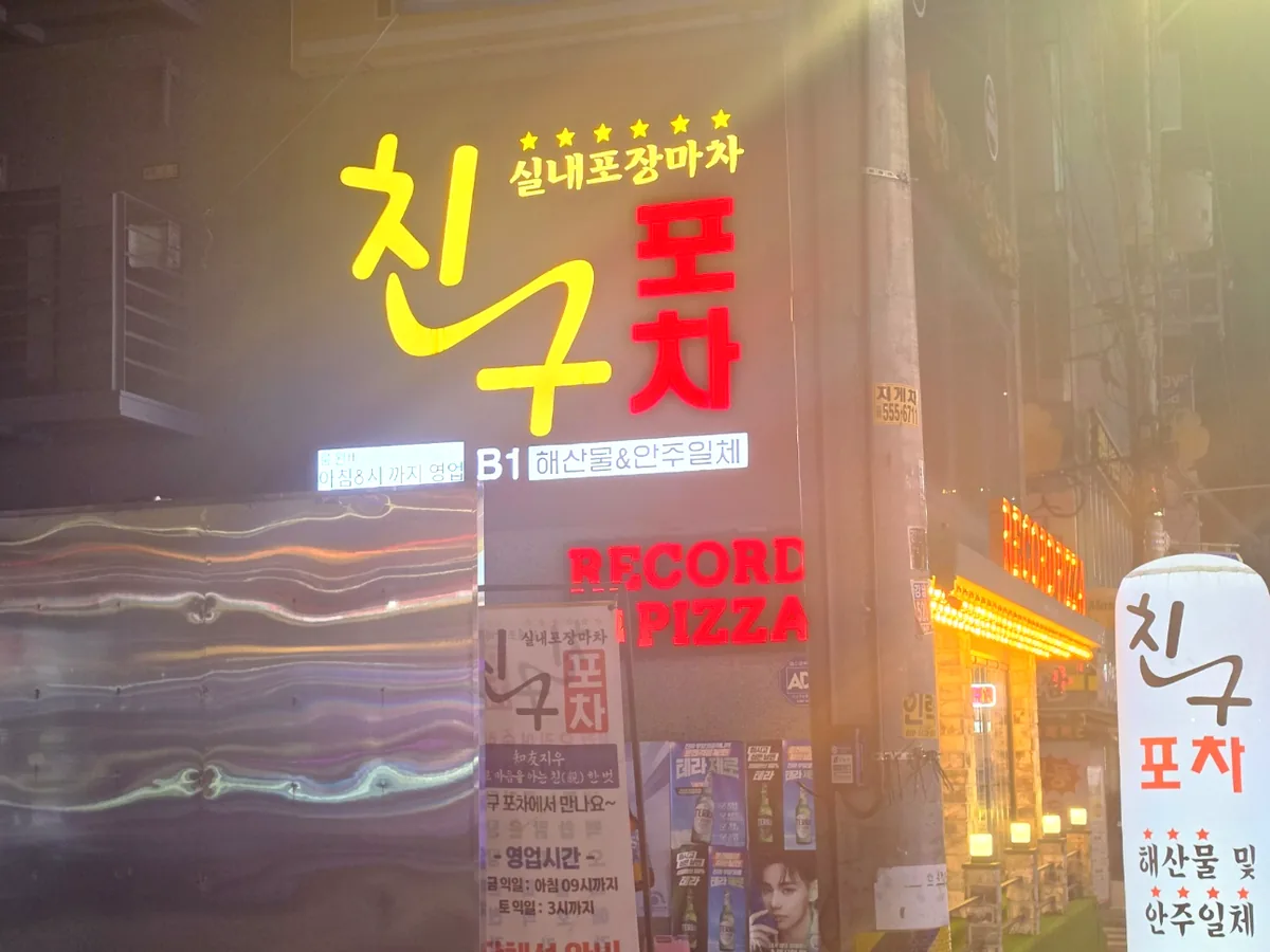 골목 어귀에서 본 친구포차 간판 야경 — 노란 친구, 빨간 포차 글씨